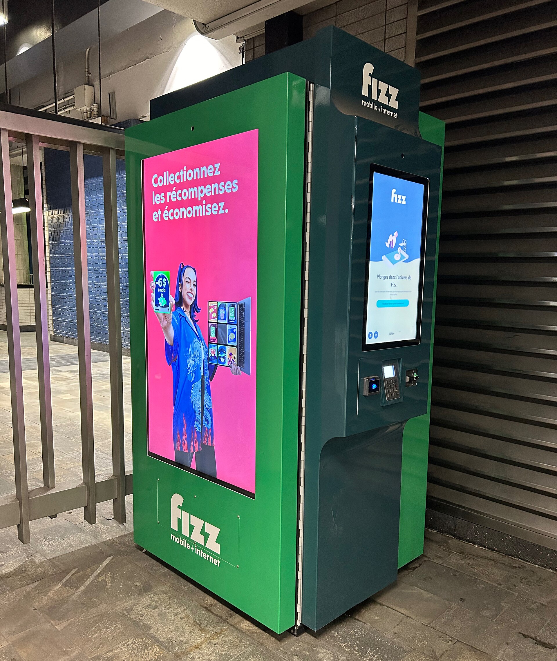 A Fizz mobile and internet kiosk is visible inside a subway station, offering rewards and savings.